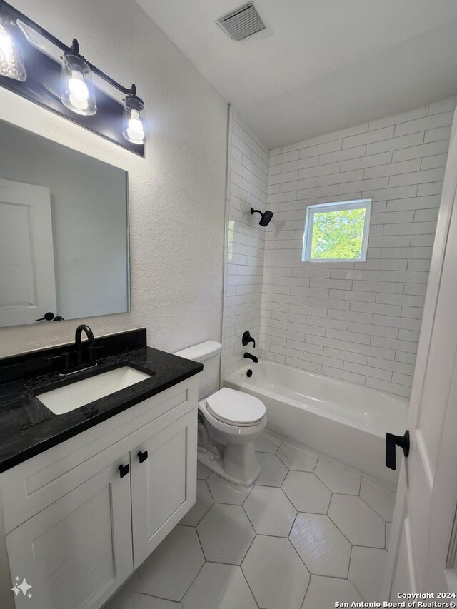 full bathroom featuring tile patterned flooring, toilet, vanity, and tiled shower / bath