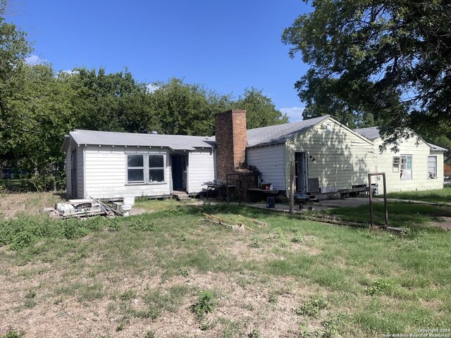 back of house with a chimney, entry steps, and a yard