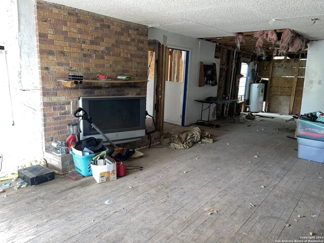 unfurnished living room featuring a textured ceiling, electric water heater, and wood-type flooring