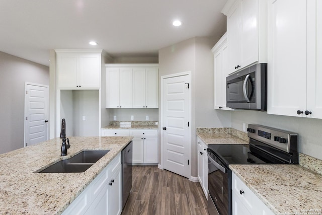 kitchen featuring light stone counters, dark wood finished floors, stainless steel appliances, white cabinetry, and a sink