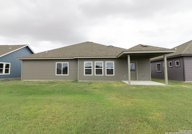 back of house with a shingled roof, a patio area, and a lawn