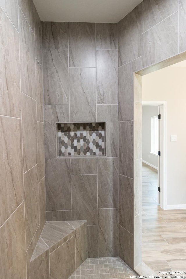 full bathroom featuring tiled shower, wood finished floors, and baseboards