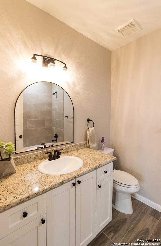 bathroom featuring visible vents, toilet, wood tiled floor, vanity, and baseboards