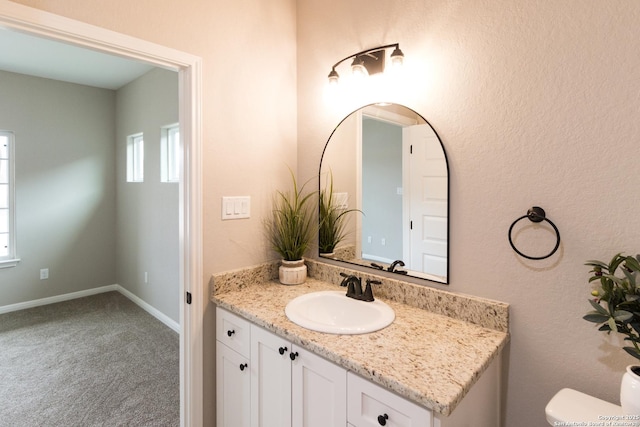 bathroom featuring toilet, plenty of natural light, baseboards, and vanity