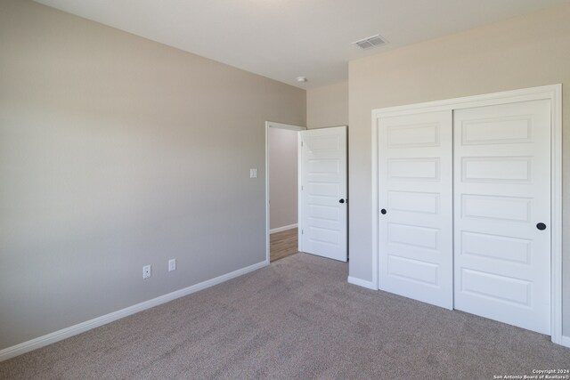 unfurnished bedroom featuring carpet, a closet, visible vents, and baseboards