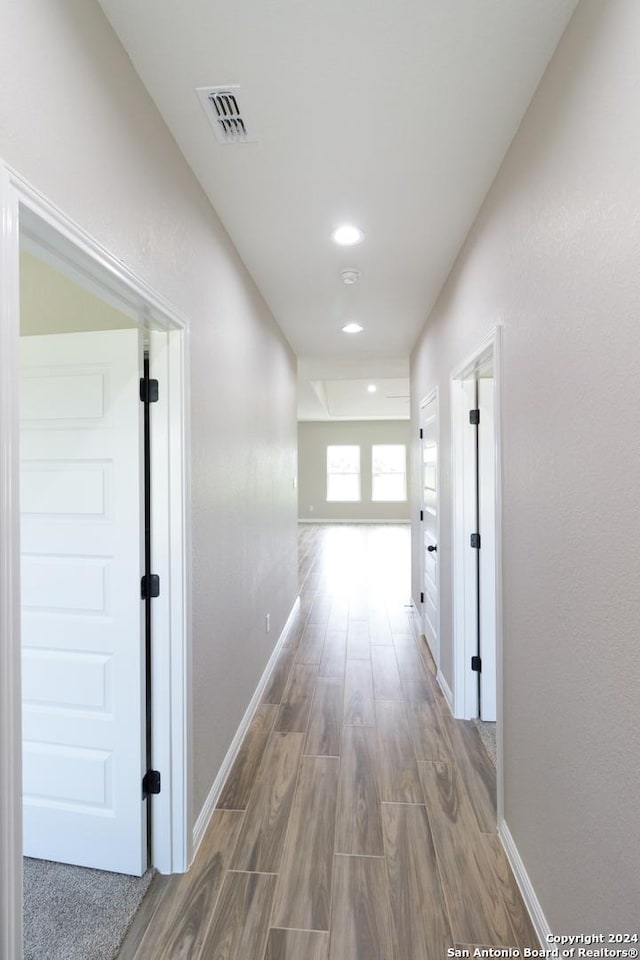 corridor with wood finished floors, visible vents, and baseboards