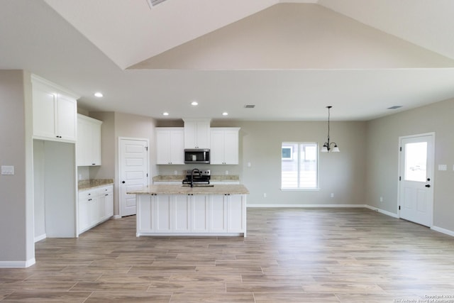 kitchen featuring stainless steel appliances, light stone counters, a center island with sink, and white cabinetry