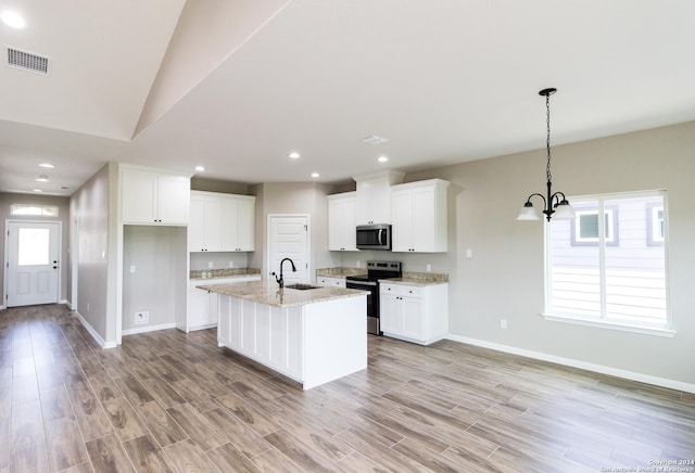 kitchen with light stone counters, visible vents, white cabinets, appliances with stainless steel finishes, and pendant lighting