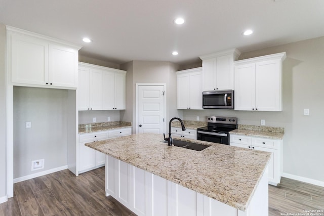 kitchen featuring appliances with stainless steel finishes, light stone counters, a kitchen island with sink, white cabinetry, and a sink