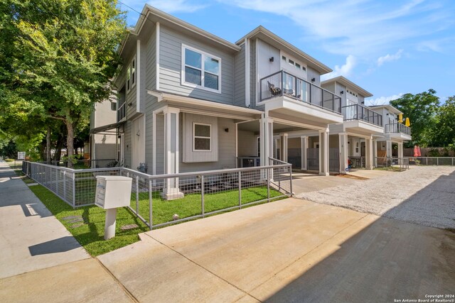 townhome / multi-family property featuring a balcony and a front lawn