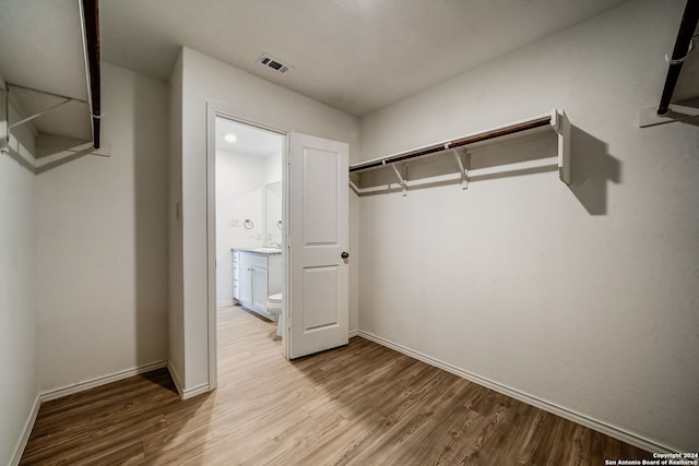 walk in closet with light hardwood / wood-style flooring