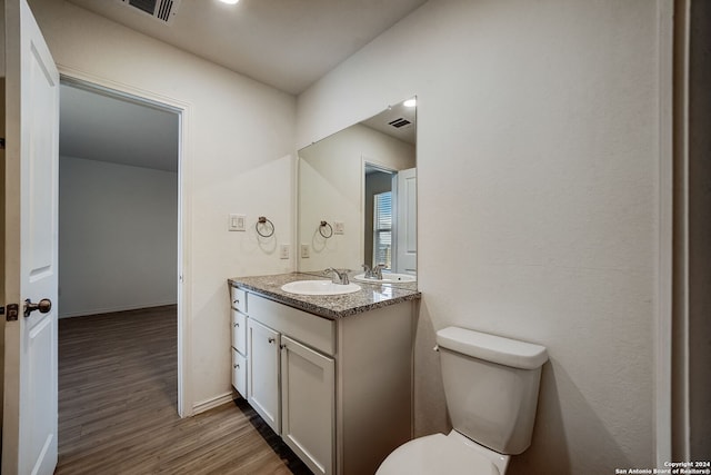 bathroom with hardwood / wood-style flooring, toilet, and vanity