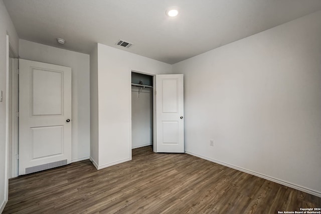 unfurnished bedroom with dark wood-type flooring and a closet