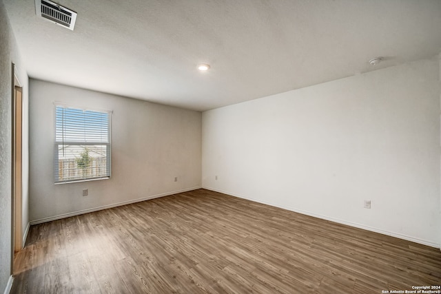 unfurnished room featuring wood-type flooring and a textured ceiling