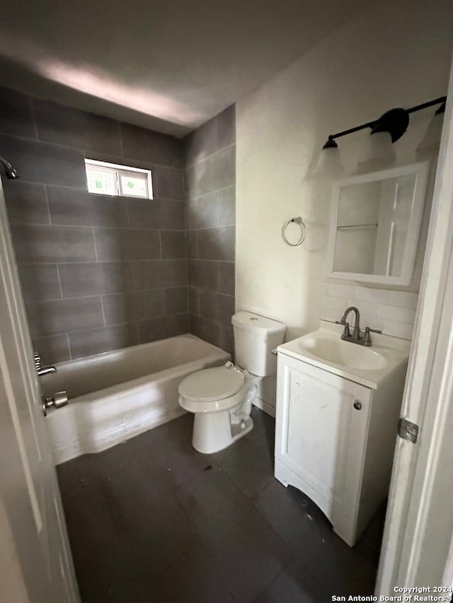 full bathroom featuring tile patterned floors, tiled shower / bath, vanity, and toilet