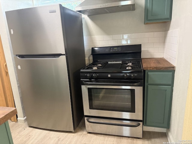 kitchen with green cabinets, light wood-type flooring, tasteful backsplash, stainless steel appliances, and extractor fan