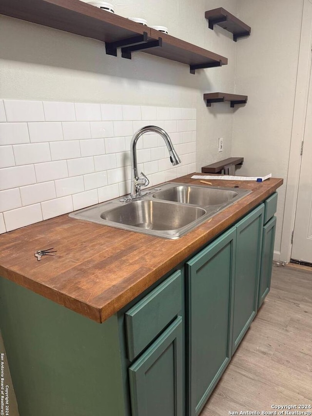 kitchen featuring wood counters, decorative backsplash, sink, light hardwood / wood-style flooring, and green cabinets