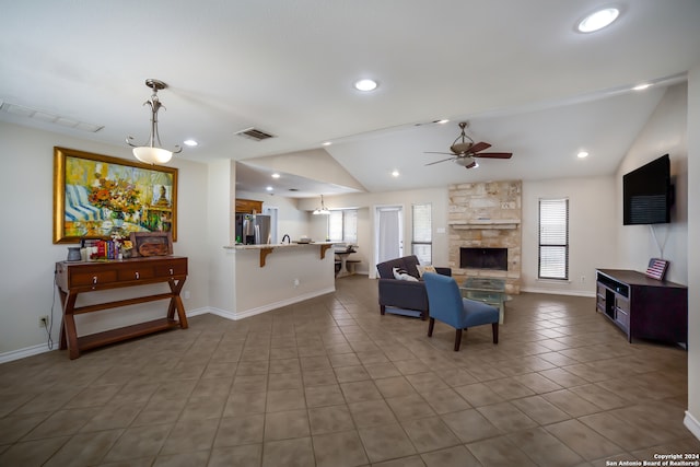 living room featuring vaulted ceiling, a fireplace, ceiling fan, and tile patterned floors