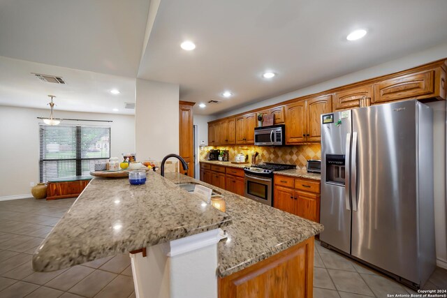 kitchen featuring hanging light fixtures, appliances with stainless steel finishes, light tile patterned flooring, and backsplash