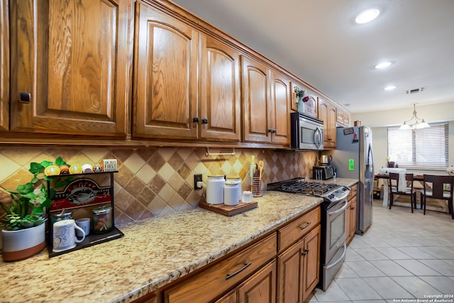 kitchen featuring appliances with stainless steel finishes, light tile patterned floors, decorative backsplash, and light stone countertops