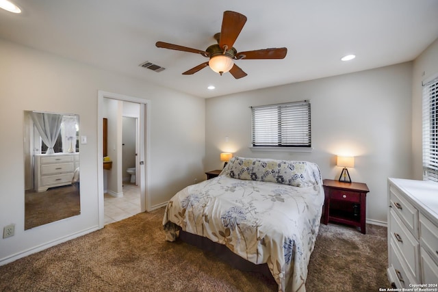 bedroom with multiple windows, light colored carpet, ensuite bathroom, and ceiling fan