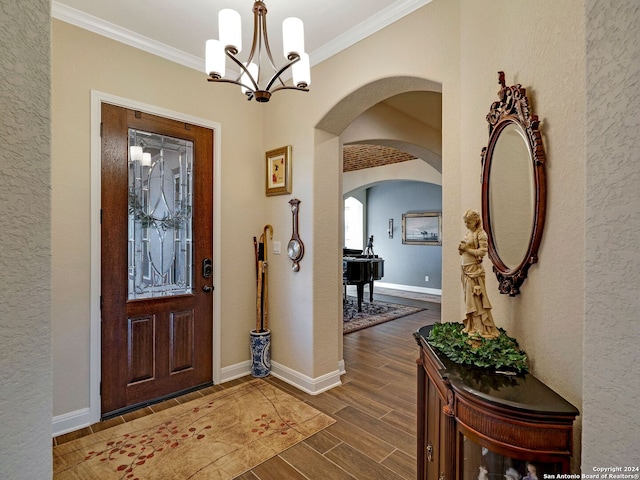 entryway with dark hardwood / wood-style floors, crown molding, and an inviting chandelier