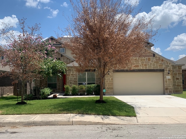 view of property hidden behind natural elements featuring a garage and a front lawn