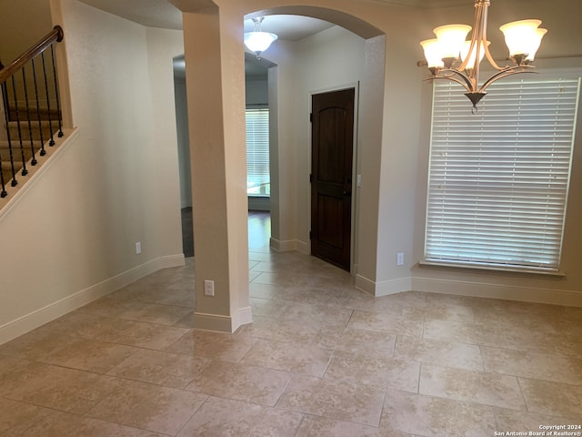 spare room featuring light tile patterned floors and a chandelier