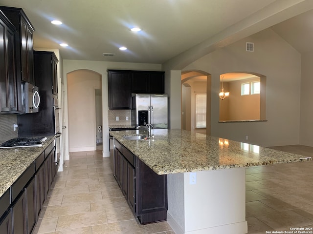 kitchen featuring light tile patterned floors, light stone countertops, appliances with stainless steel finishes, decorative backsplash, and sink