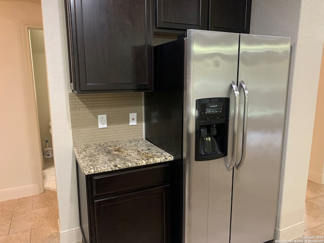 kitchen featuring light tile patterned floors, light stone counters, decorative backsplash, dark brown cabinetry, and stainless steel refrigerator with ice dispenser