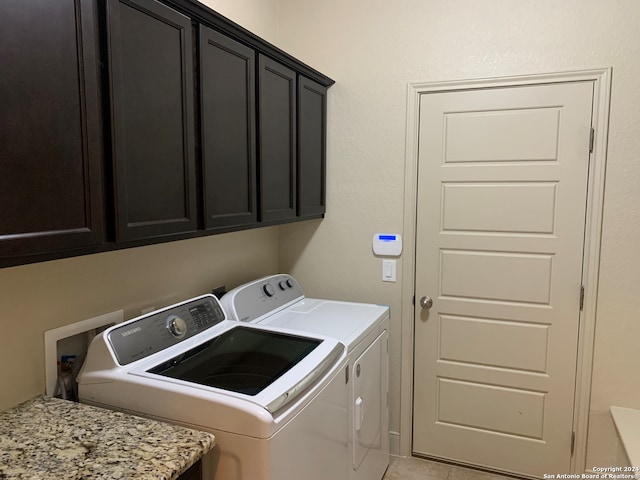 clothes washing area with washing machine and clothes dryer, light tile patterned flooring, and cabinets