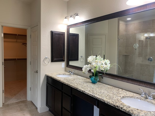 bathroom with tile patterned flooring, a tile shower, and dual bowl vanity