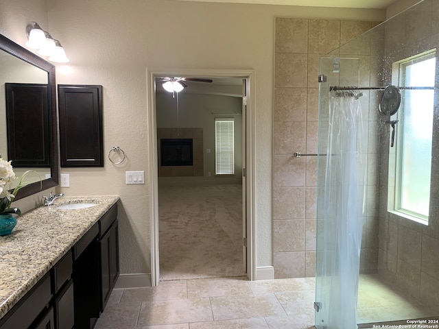 bathroom with vanity, tile patterned floors, a tiled fireplace, and ceiling fan