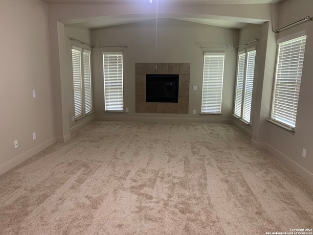 unfurnished living room with a fireplace, vaulted ceiling, and light colored carpet