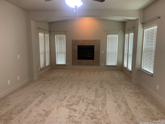 unfurnished living room featuring light carpet, lofted ceiling, ceiling fan, and a tiled fireplace