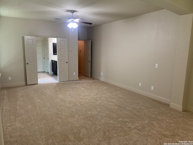 unfurnished bedroom featuring connected bathroom, light colored carpet, and ceiling fan