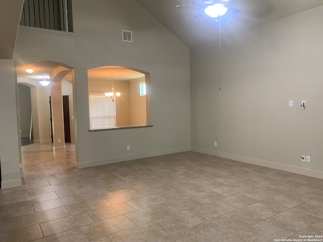 spare room featuring ceiling fan with notable chandelier, light tile patterned floors, and high vaulted ceiling