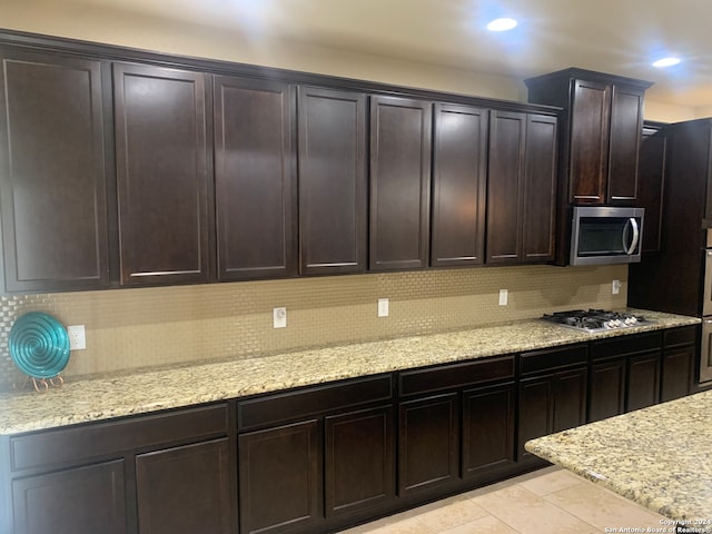 kitchen featuring light stone counters, tasteful backsplash, stainless steel appliances, and light tile patterned floors