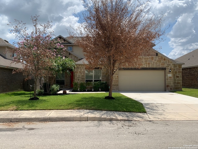 view of property hidden behind natural elements featuring a garage and a front yard