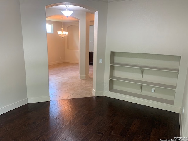 spare room with a notable chandelier and hardwood / wood-style floors