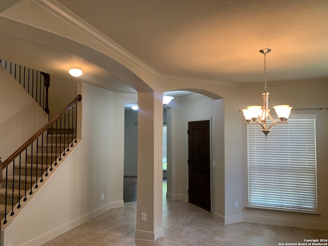 interior space with an inviting chandelier, light tile patterned floors, and ornamental molding