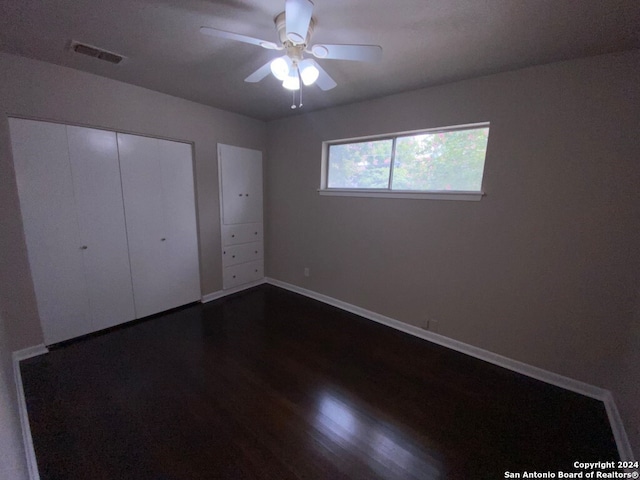 unfurnished bedroom featuring ceiling fan, dark hardwood / wood-style flooring, and a closet