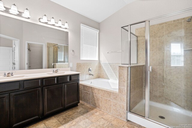 bathroom with plus walk in shower, lofted ceiling, tile patterned flooring, and double vanity