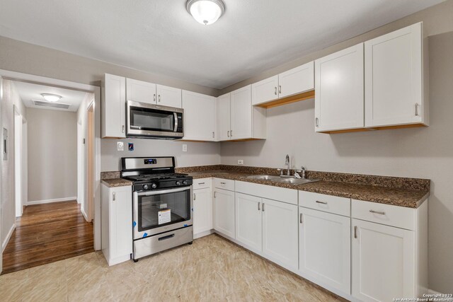 kitchen featuring visible vents, appliances with stainless steel finishes, white cabinets, and a sink