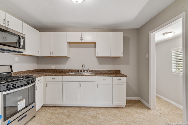 kitchen featuring light tile patterned flooring, sink, appliances with stainless steel finishes, and white cabinetry