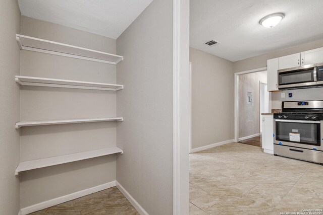 kitchen with white cabinets, appliances with stainless steel finishes, and light tile patterned floors