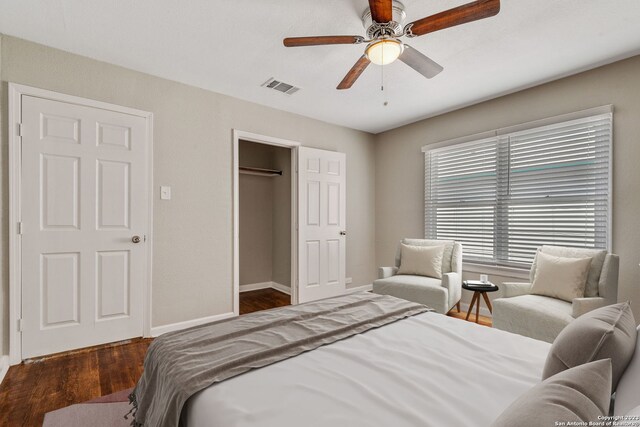 bedroom with ceiling fan, dark hardwood / wood-style floors, and a walk in closet