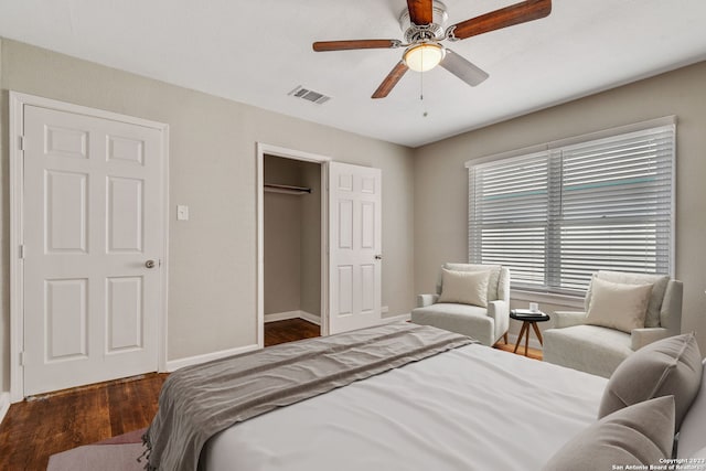 bedroom with baseboards, visible vents, ceiling fan, wood finished floors, and a closet