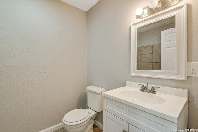 bathroom featuring toilet, vanity, and baseboards