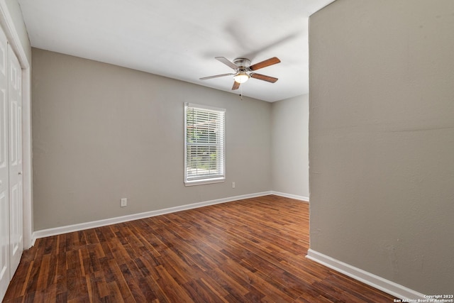 empty room featuring ceiling fan, baseboards, and dark wood-type flooring